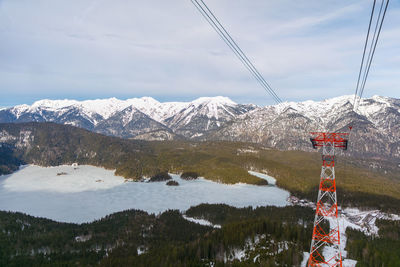 Overhead cable car over snow covered mountains against sky