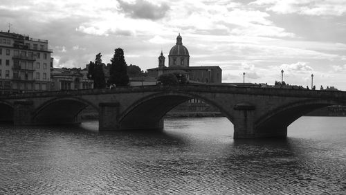 Arch bridge over river against buildings in city