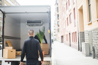 Rear view of man walking on street amidst buildings