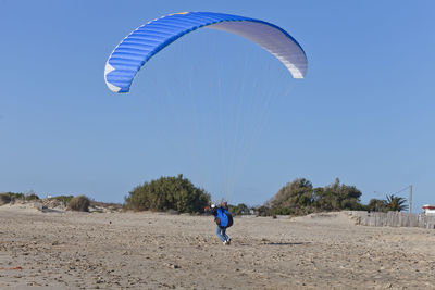 Person paragliding against clear sky