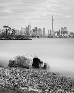 View of city by river against cloudy sky