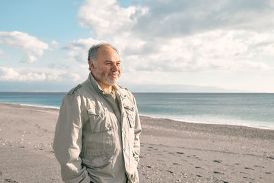 Happy middle-aged bearded man walking along deserted winter beach. concept of leisure activities