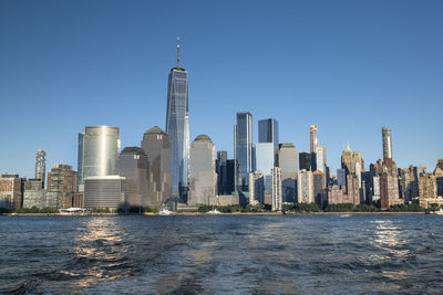 Sea by modern buildings against clear sky