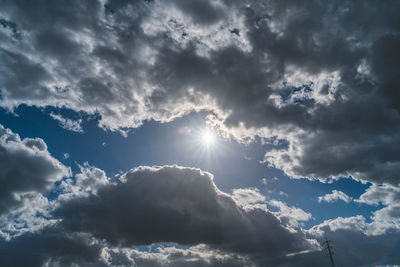 Low angle view of sunlight streaming through clouds