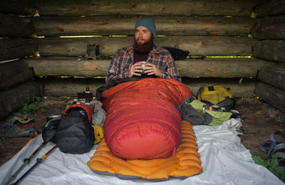 Man having drink while sitting in log cabin