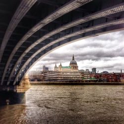 Bridge over river against cloudy sky