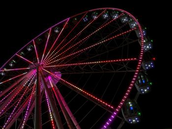 Low angle view of illuminated ferris wheel against sky at night