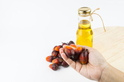 Cropped image of person holding fruit against white background