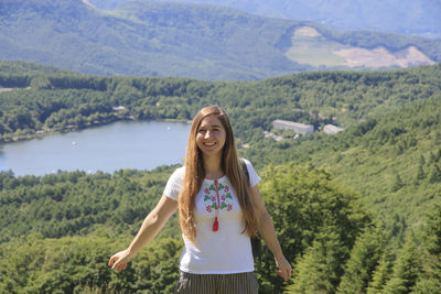 Portrait of smiling young woman standing on mountain