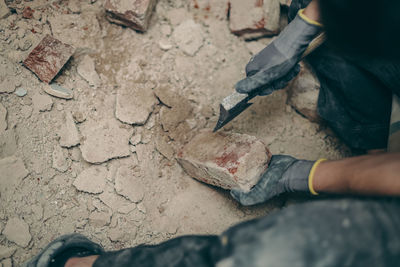 A young man cleans bricks with an axe.