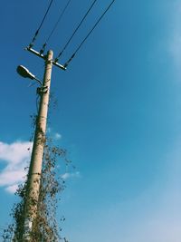 Low angle view of power lines against blue sky