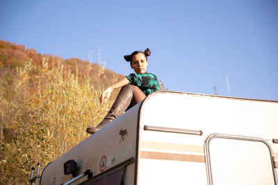 Low angle view of woman sitting on field against clear sky