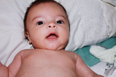 High angle view of shirtless baby boy lying on bed at home