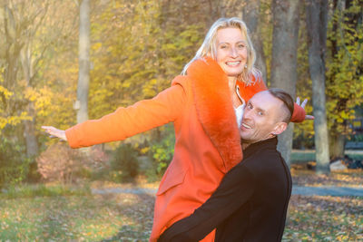 Woman with arms outstretched standing by trees during autumn
