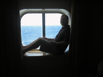 Man looking through window at sea