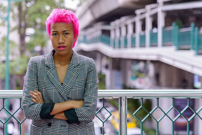 Portrait of woman standing against railing