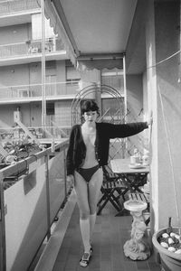 Full length portrait of woman standing by building