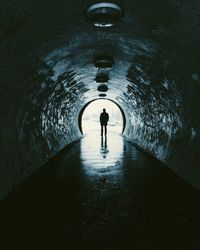 Rear view of silhouette man standing at the tunnel end