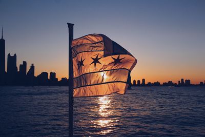 Silhouette sailboat by sea against clear sky during sunset