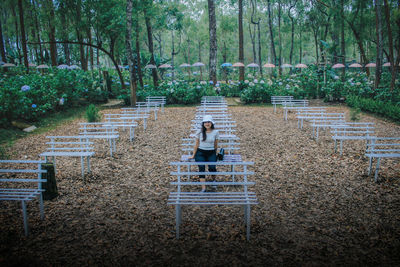 Young woman sitting on bench in park during autumn