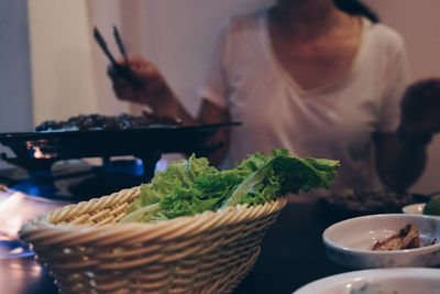 Close-up of woman holding smart phone in basket on table