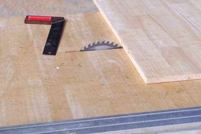 High angle view of hand saw on wooden plank