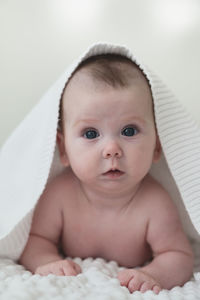 Portrait of cute baby girl lying on bed