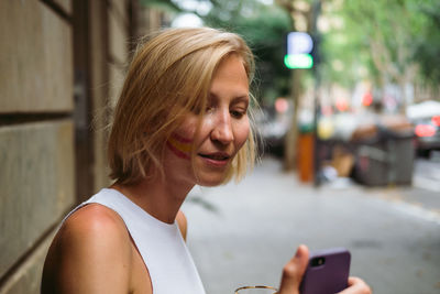 Portrait of smiling young woman using mobile phone in city