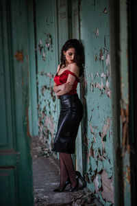 Portrait of young woman standing against door