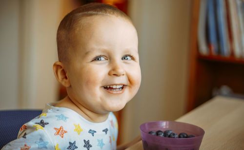 Portrait of cute baby boy eating blueberries at home
