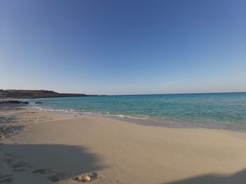 Scenic view of beach against clear blue sky