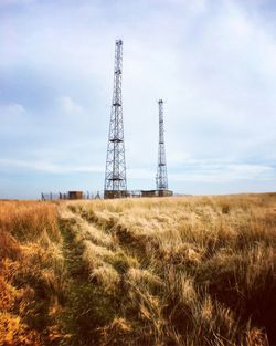 Low angle view of electricity pylon on field against sky