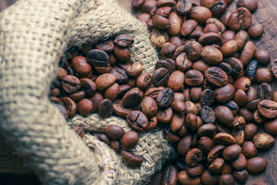 High angle view of roasted coffee bean spilled from jute bag