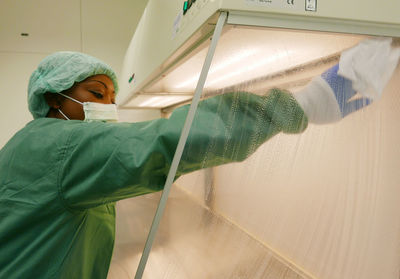 Side view of nurse cleaning glass at hospital