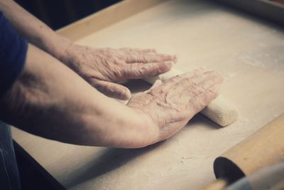 Close-up of hands kneading dough on table