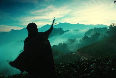 Rear view of silhouette woman standing on mountain against sky