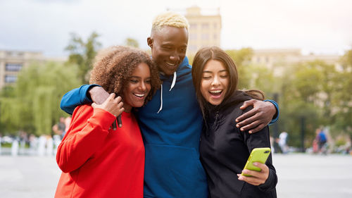 Smiling friends taking selfie while standing outdoors