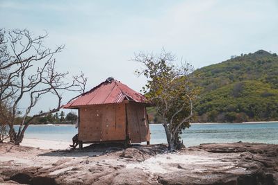 House on beach by trees against sky