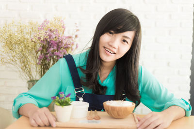 Portrait of a smiling young woman sitting on table