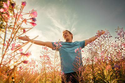 Rear view of woman with arms outstretched standing on field