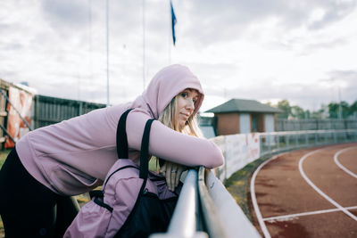 Woman stood by a running track looking thoughtful