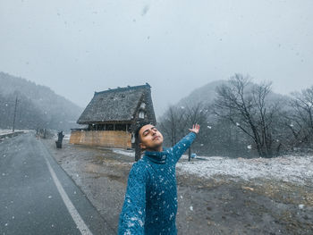 Full length of woman standing on snow covered landscape during rainy season