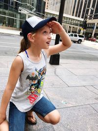 Young woman looking away while standing on street in city