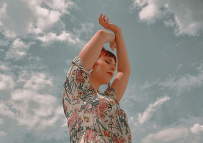 Midsection of young woman looking at camera against sky