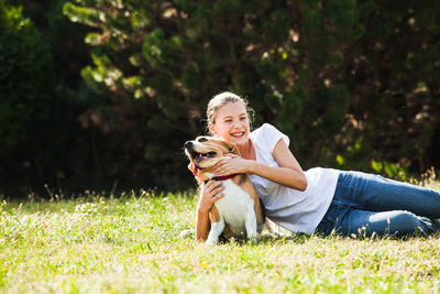 Girl with dog on grass against trees