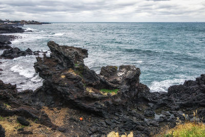 Rock formation on sea shore against sky