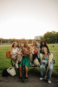 Portrait of happy teenage girls sitting on bench at park