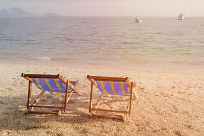 Chairs on beach against sky