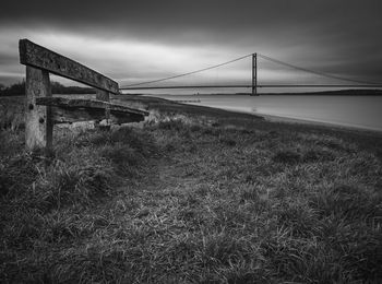 View of suspension bridge on field against sky