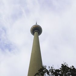 Low angle view of communications tower against cloudy sky
